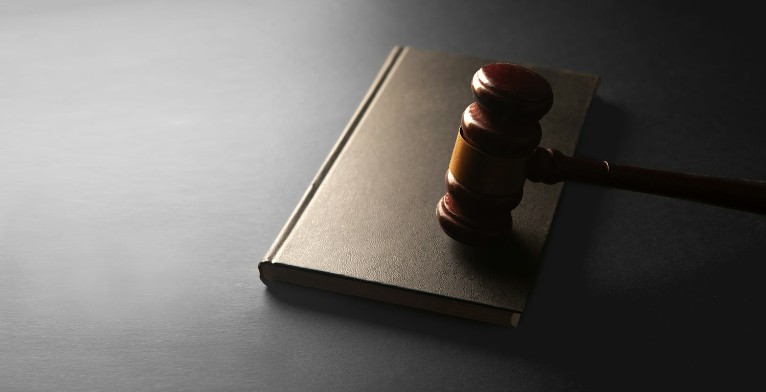 A wooden judge's gavel resting on a closed law book, symbolizing legal compliance