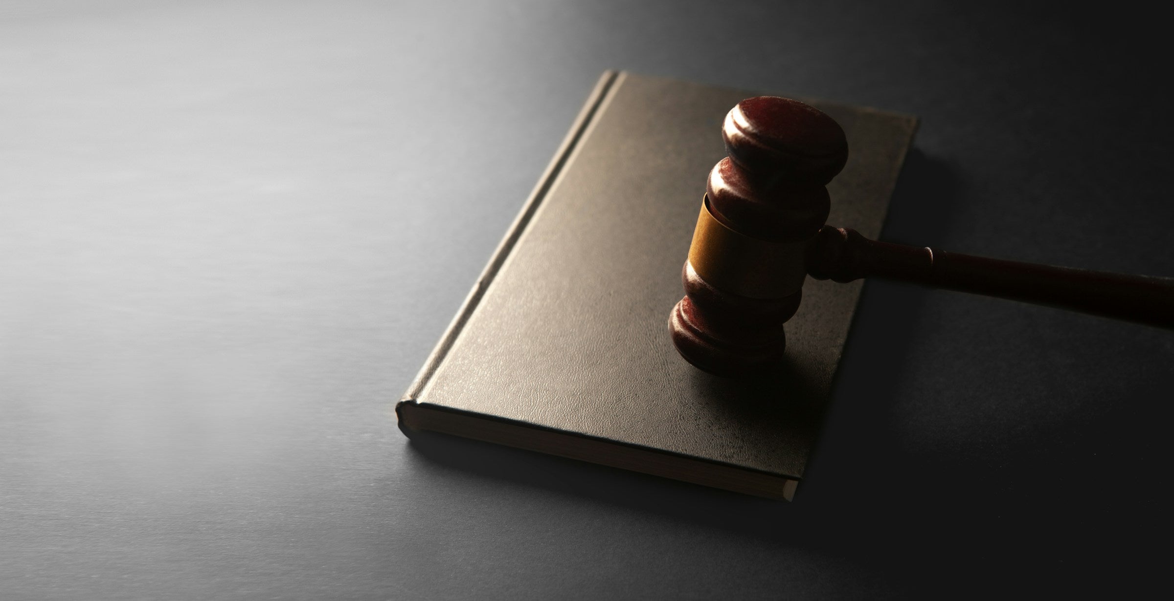 A wooden judge's gavel resting on a closed law book, symbolizing legal compliance